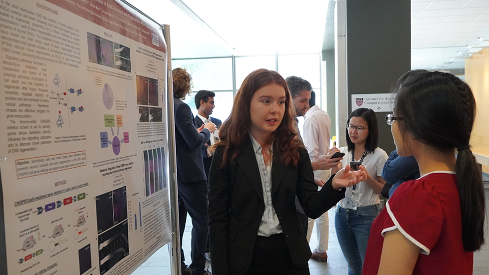 Two students speak in front of a poster.