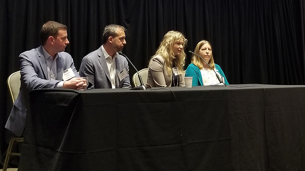 Four panelists in an auditorium