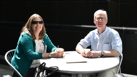Jessica MacDonald and Jeff Macklis sit in the sun in front of a fountain