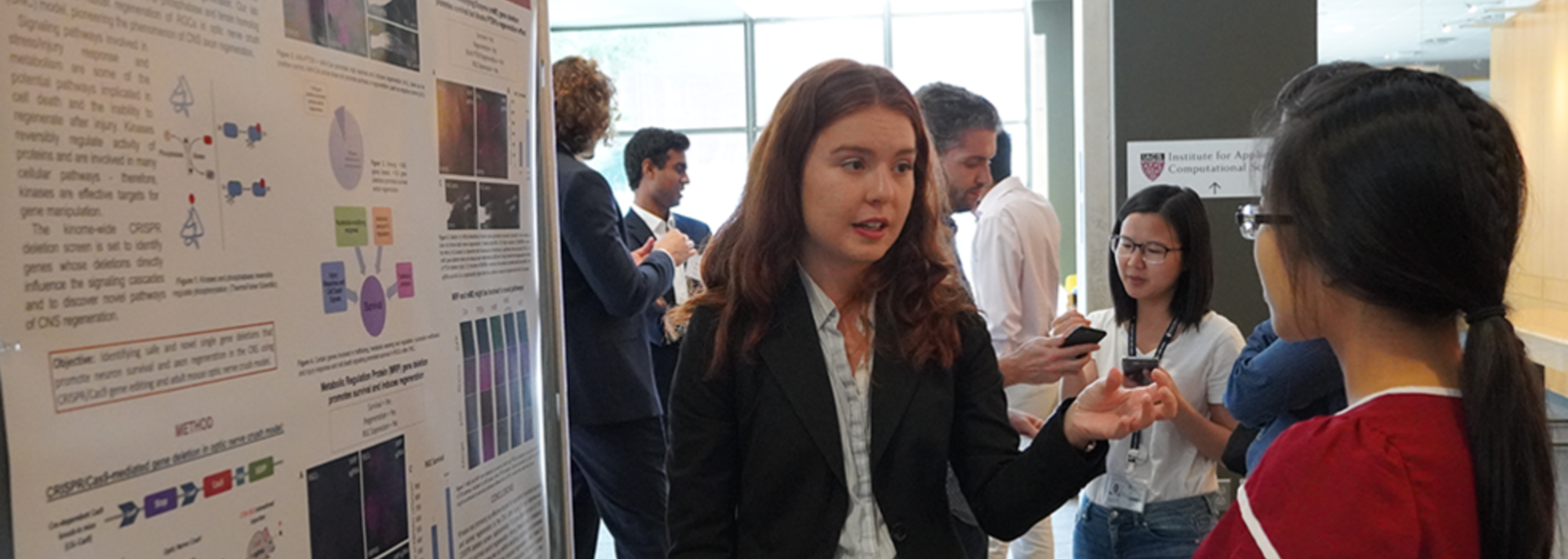 Two students speak in front of a poster.