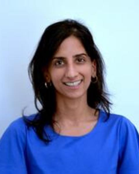 Woman with shoulder length dark hair wearing a bright blue shirt